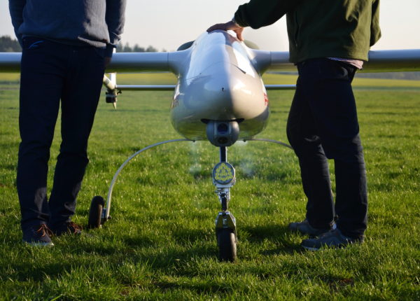 Deux personnes debout derrière un drone sur une pelouse