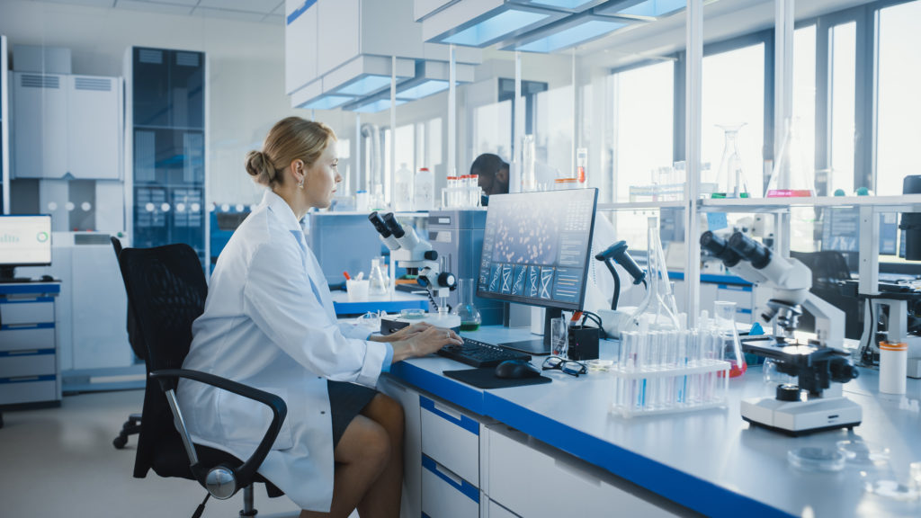 Femme en blouse de laboratoire à l'ordinateur