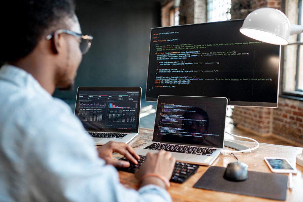 Homme à un bureau devant plusieurs ordinateurs