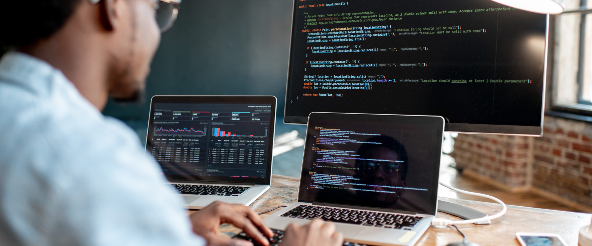 Homme à un bureau devant plusieurs ordinateurs