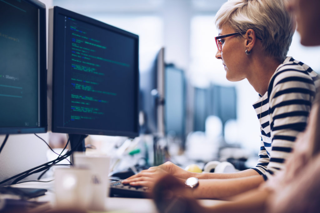 Femme assise devant un ordinateur affichant du code