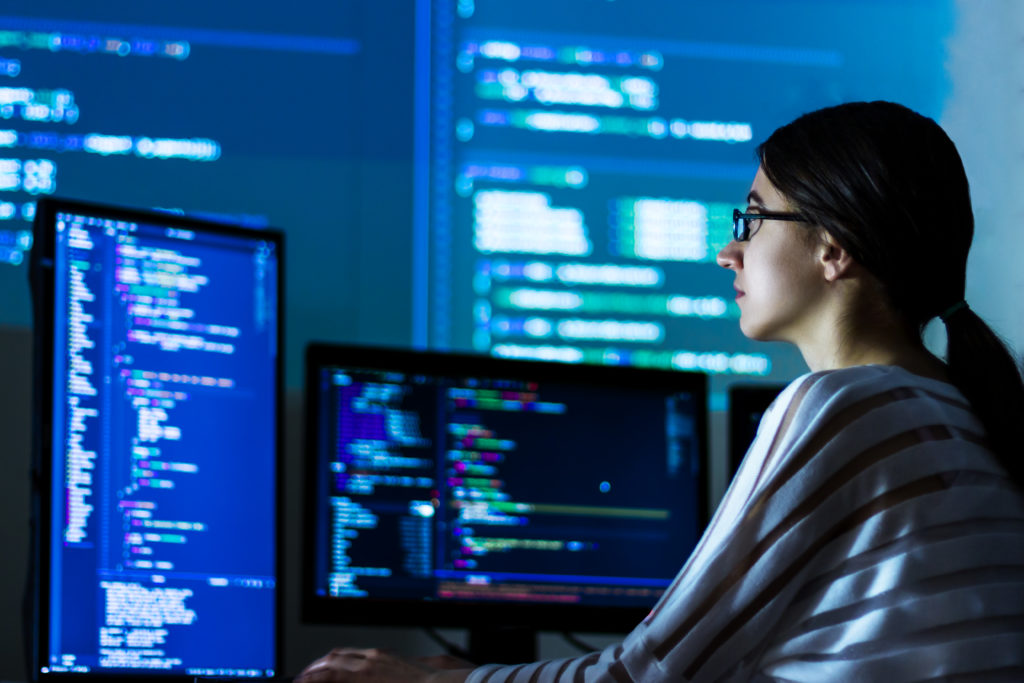 Femme assise devant un ordinateur affichant du code