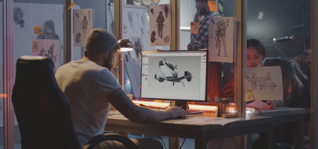 Homme assis à un bureau devant un moniteur montrant un drone